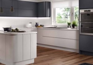 Modern kitchen with dark cabinets, white countertops, built-in oven, and wood flooring.