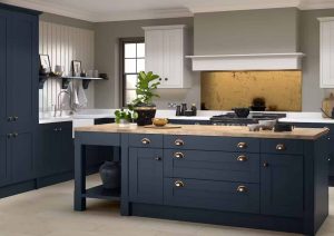 Modern kitchen with navy cabinets, gold handles, and a central island with a wooden countertop.