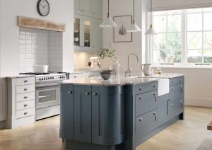 Modern kitchen with a blue island, white cabinets, large window, and stainless steel appliances.