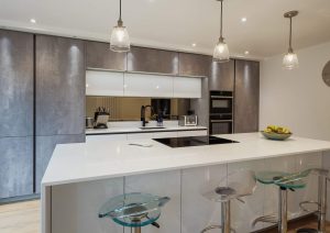 Modern kitchen with a large island, built-in appliances, and clear bar stools.