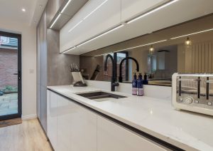 Modern kitchen with white countertops, black faucet, toaster, and a door leading outside.