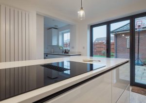 Modern kitchen with a sleek stove and large glass doors leading to a patio with a basketball hoop outside.