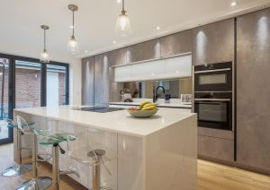 Modern kitchen with a large island, bar stools, built-in appliances, and pendant lights.