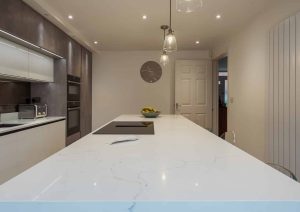 Modern kitchen with a large white island, built-in appliances, and pendant lights.