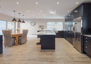 Modern kitchen with dark cabinets, a center island, and a dining table with chairs.