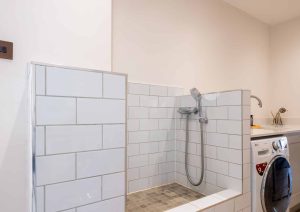 A tiled pet washing station next to a washing machine and sink in a laundry room.