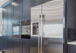 Modern kitchen with blue cabinets and a stainless steel refrigerator.
