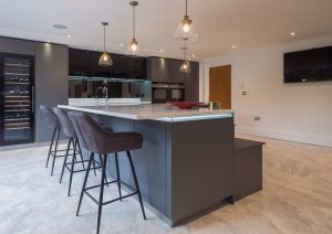 Modern kitchen with a large island, bar stools, pendant lights, and built-in appliances.