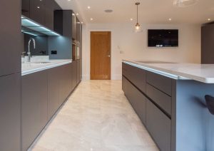 Modern kitchen with dark cabinets, a large island, and light tile flooring.
