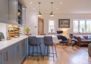 Modern kitchen and living area with blue cabinets, island seating, and natural light.