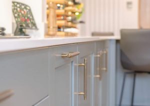 Modern kitchen cabinets with gold handles and a gray chair in the background.